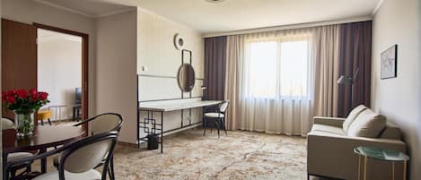 A hotel room with a dining area, a sofa, and a small table.