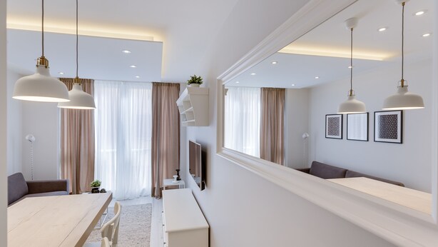 A modern, well-lit room with a dining table, chairs, a bench, and a long counter.
