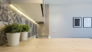 A modern bathroom with a wooden vanity, two potted plants, a sink, and a shower area.