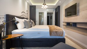 A modern bedroom with a large bed, a bedside table, a lamp, a TV mounted on the wall, and a ceiling light fixture.