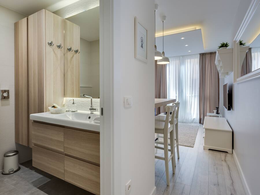 A modern bathroom with a large mirror, two sinks, and wooden cabinetry.