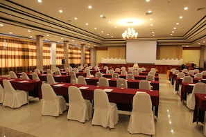 Conference room with tables, chairs, and a large screen for presentations.
