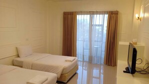 Habitación de hotel con dos camas, un televisor y una ventana con cortinas.