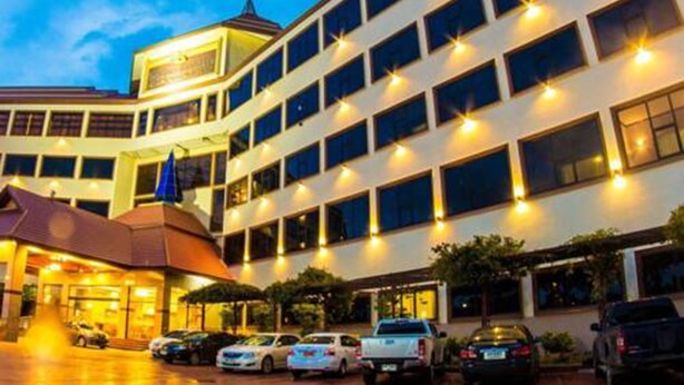 Un hotel de varios pisos con un atrio central, varios espacios de estacionamiento y una bandera en el edificio.
