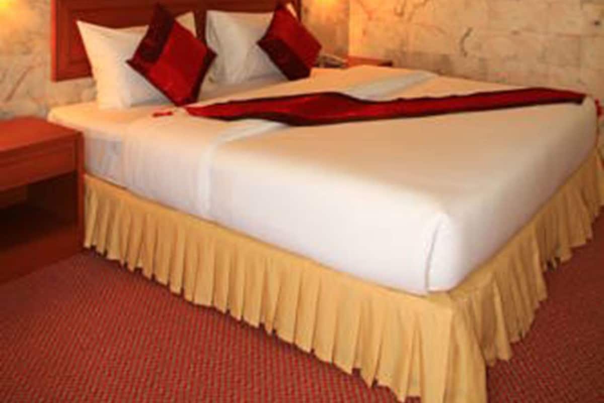 Ein Hotelzimmer mit Steinwand, einem Bett mit weißer Bettwäsche, roten Kissen und einem Gemälde an der Wand.