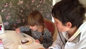 Un tavolo da pranzo con una tovaglia fiorata, un vassoio con una tazza di caffè e un piatto di cibo, e un bollitore.