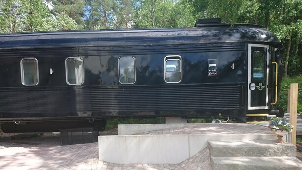 Un vagone ferroviario nero con una porta, finestre e un piccolo cartello.