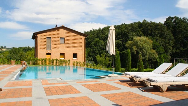 Une piscine avec des chaises longues et un bâtiment doté d’une façade ornée de motifs.
