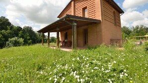 Une maison en briques avec un patio couvert et un jardin à l’avant.