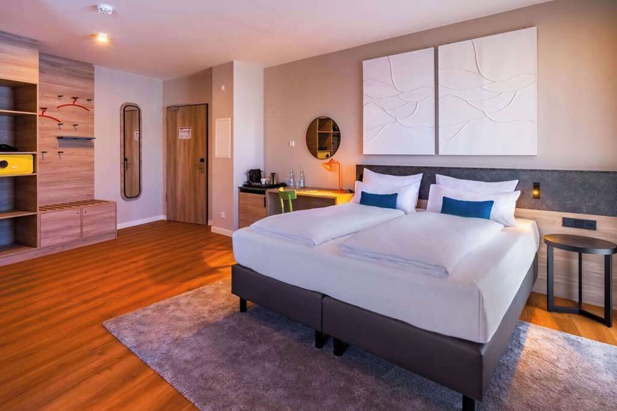 Una habitación de hotel moderna con una cama grande, un escritorio y un armario.