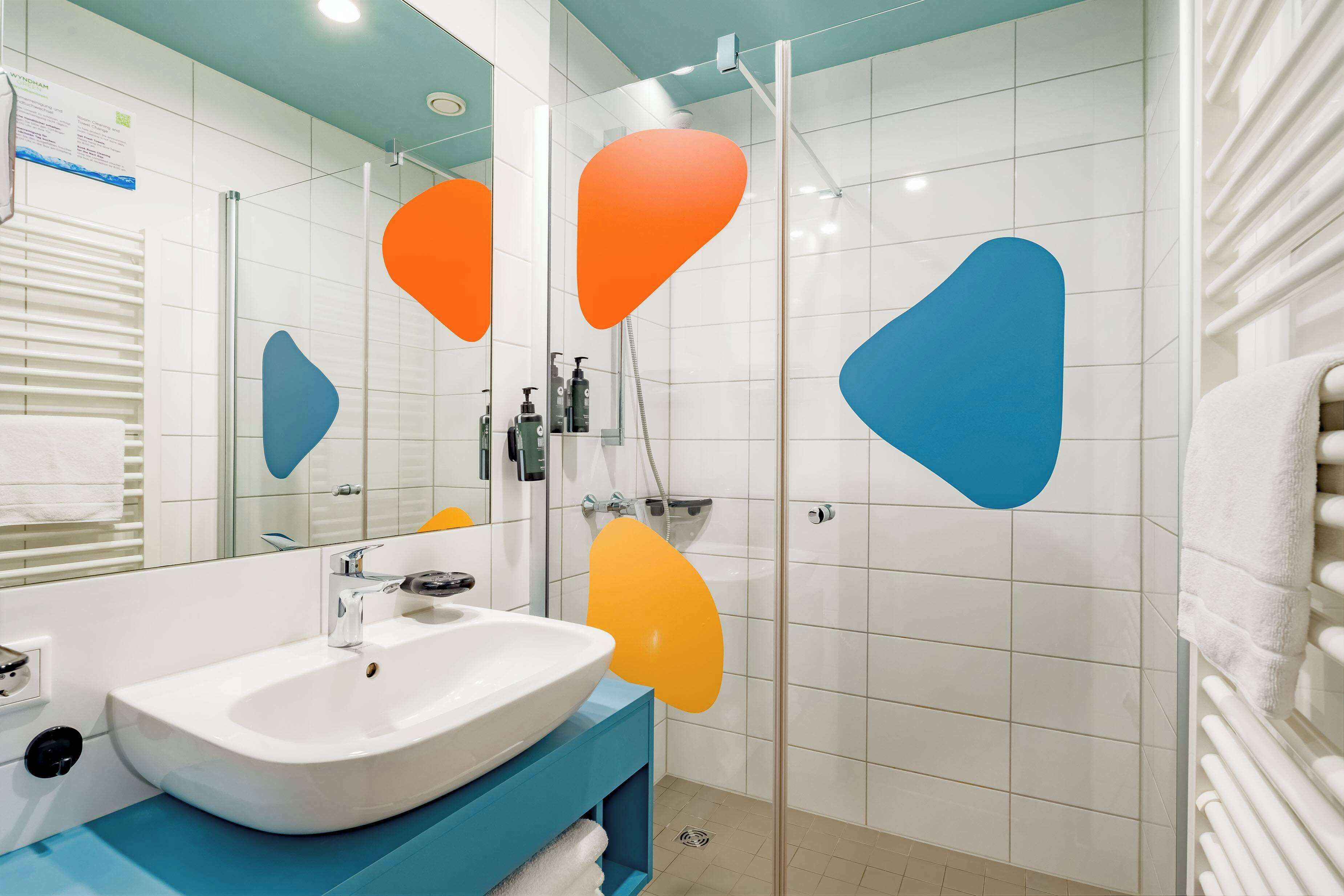 A bathroom with a white sink, blue vanity, and a glass shower enclosure.