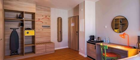Une chambre d’hôtel avec une armoire en bois, un bureau avec une chaise, un lit et une petite kitchenette.