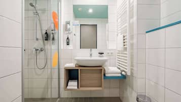 A modern bathroom with a glass shower enclosure, a sink with a mirror above, and a towel rack.