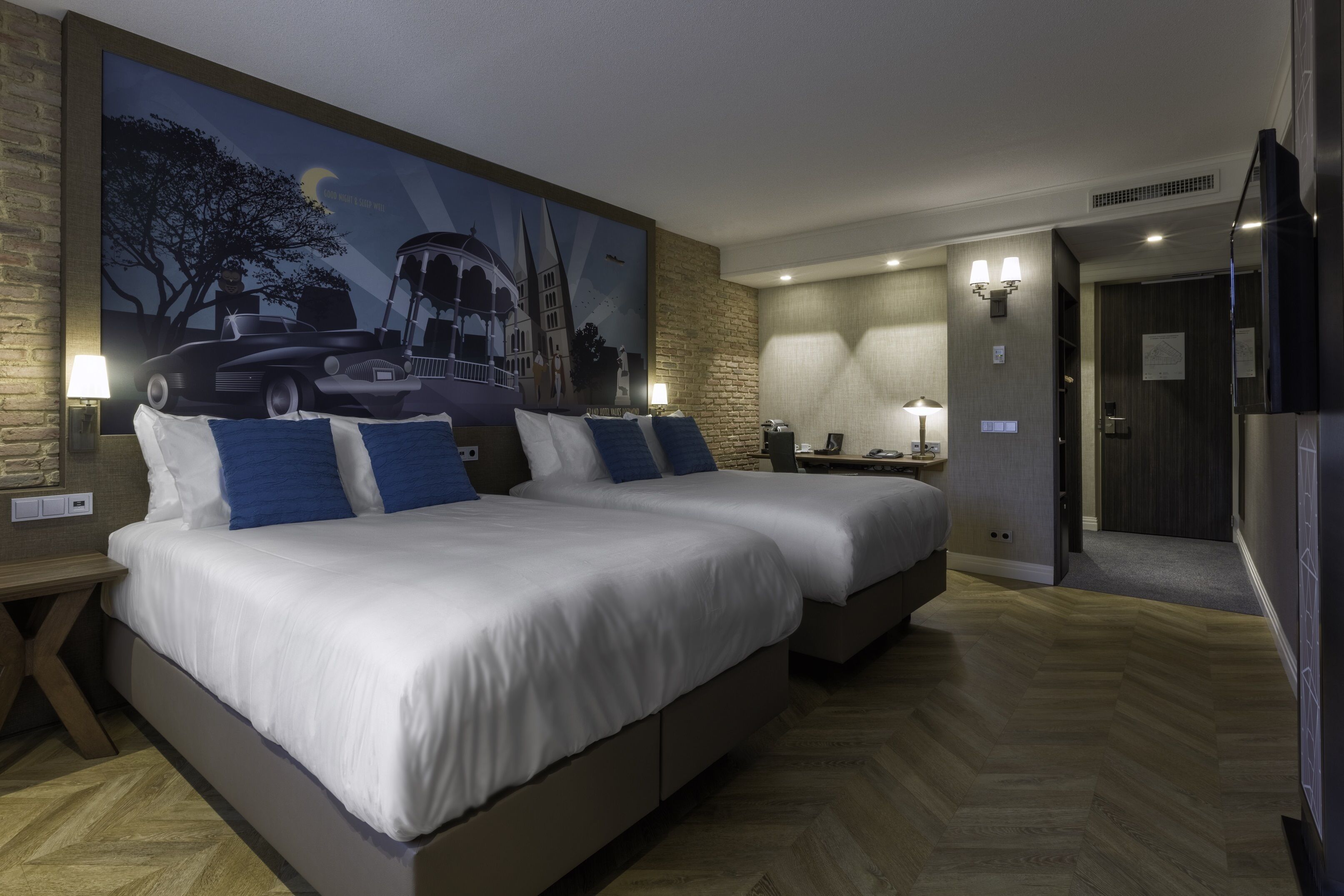 Ein Hotelzimmer mit zwei Betten, einem großen Gemälde an der Wand und Holzboden.