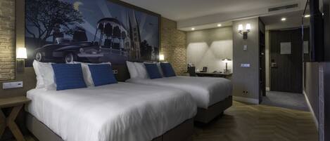 A hotel room with two beds, a large painting on the wall, and a wooden floor.