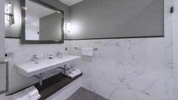 A modern bathroom with a large mirror, two sinks, and a towel rack.