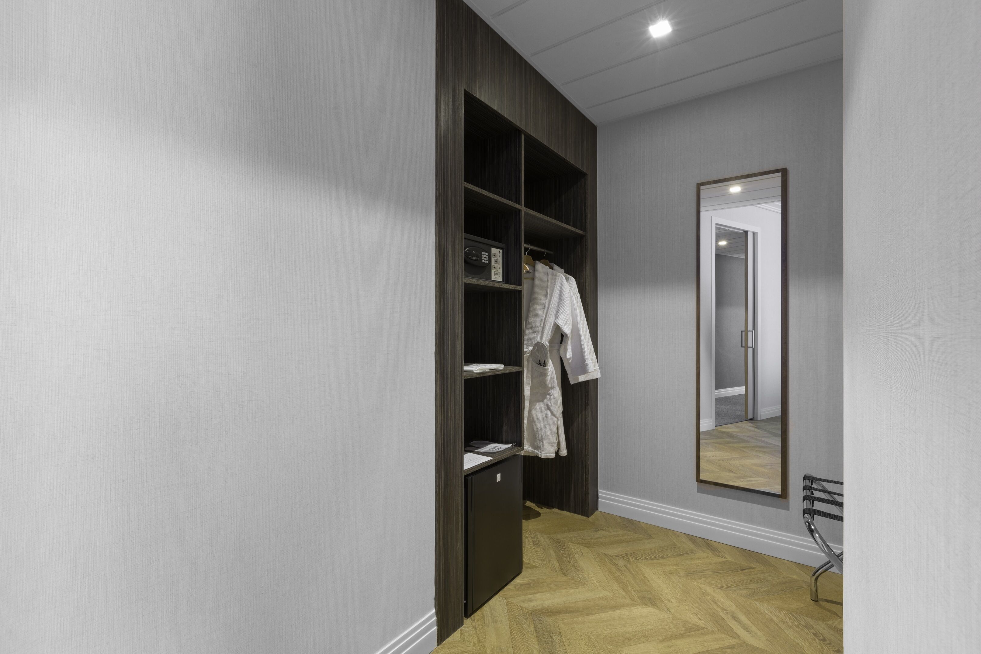 Un baño moderno con tocador de madera, un espejo y un perchero para toallas.
