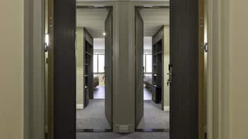 A hallway with mirrored doors leading to a room with a bed and a desk.