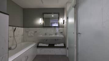 A modern bathroom with a bathtub, a sink with a mirror above, and a shower area.