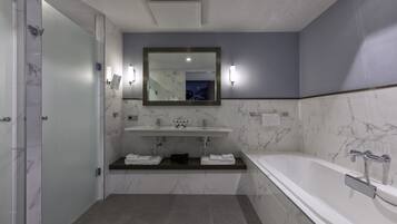 A modern bathroom with a marble vanity, a large mirror, and a bathtub.