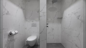 Ein modernes Badezimmer mit Toilette, Marmorwänden und einer Duschkabine.