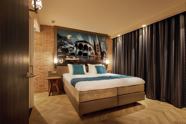 Una habitación de hotel moderna con una cama grande, una mesita de noche de madera, una pared de ladrillo decorativa y un mural de un paisaje urbano.