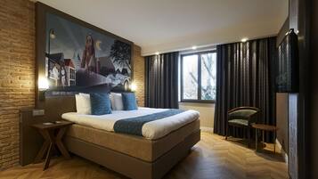 Habitación de hotel moderna con una cama grande, un mural de paisaje urbano, una mesita, una silla y un televisor.