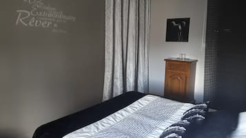Un dormitorio con una cama, un aparador de madera, una pared con una cita y una ventana con cortinas.