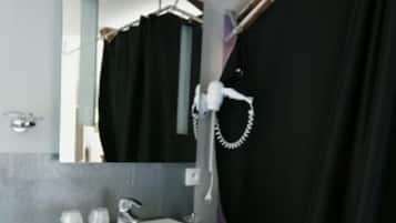 Ein Badezimmer mit weißem Waschbecken, Spiegel und Handtuchhalter.