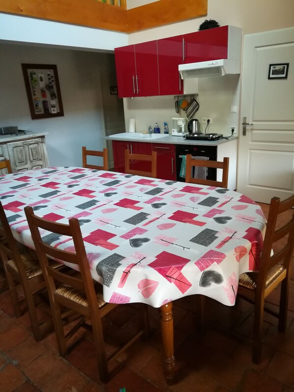 A dining area with a table covered in a patterned tablecloth, surrounded by wooden chairs. - L'Escampette (Saint-Aubin-en-Charollais)