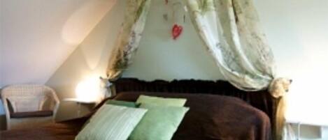 Un dormitorio con una cama grande, una silla, una mesita de noche y un dosel.