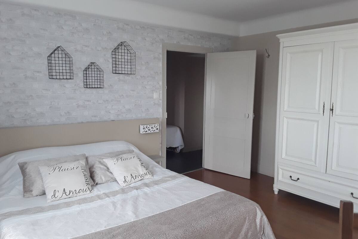 Une chambre à coucher comprenant un lit, une armoire et une porte donnant sur une autre pièce.
