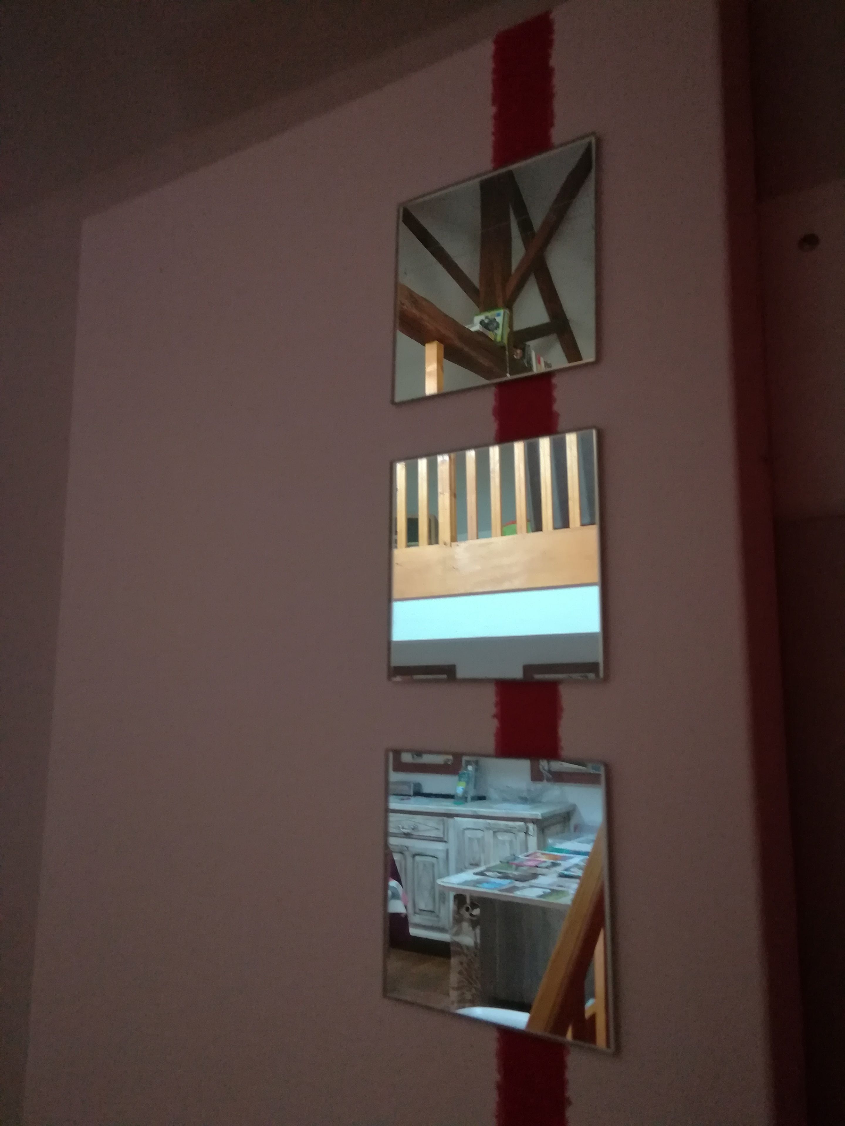 Una pared con tres espejos de distintos tamaños.