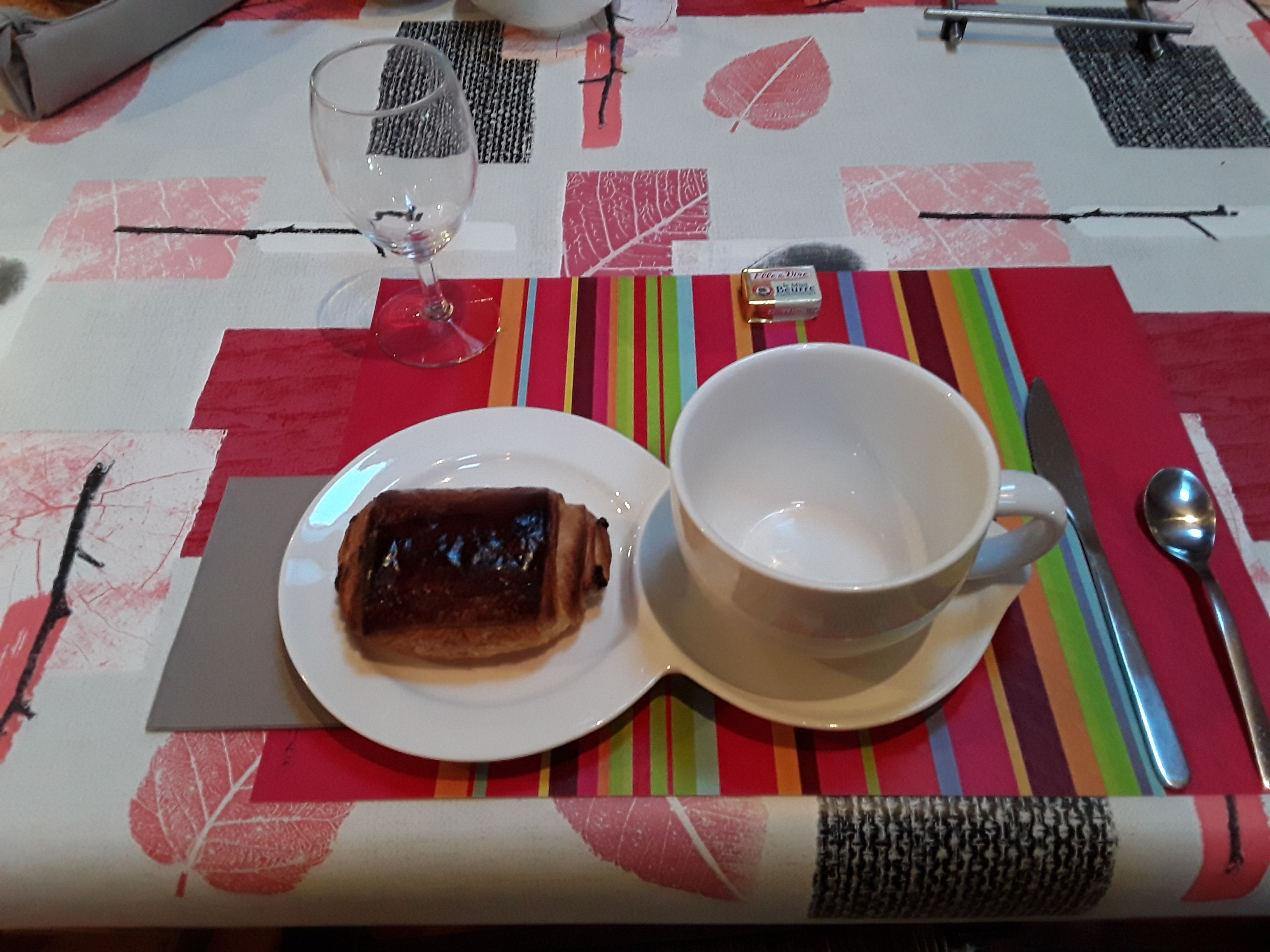 Una mesa con un plato de comida, una taza y cubiertos.