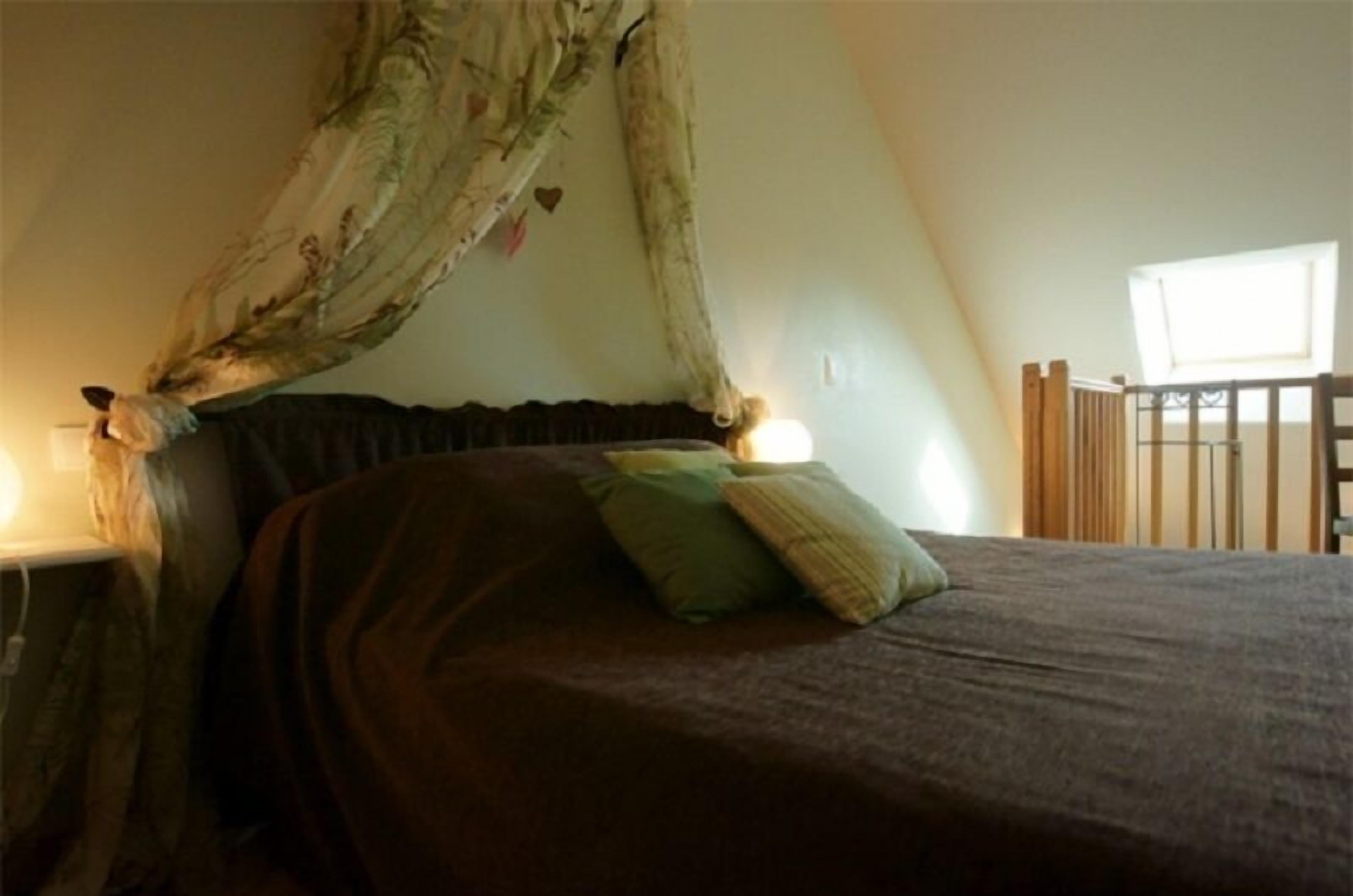 Un dormitorio con cama a dosel, una mesita de noche y una ventana con vistas al exterior.