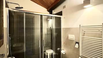 Une salle de bain dotée d’une douche à parois de verre, d’un lavabo blanc, d’un bidet et d’un porte-serviettes.