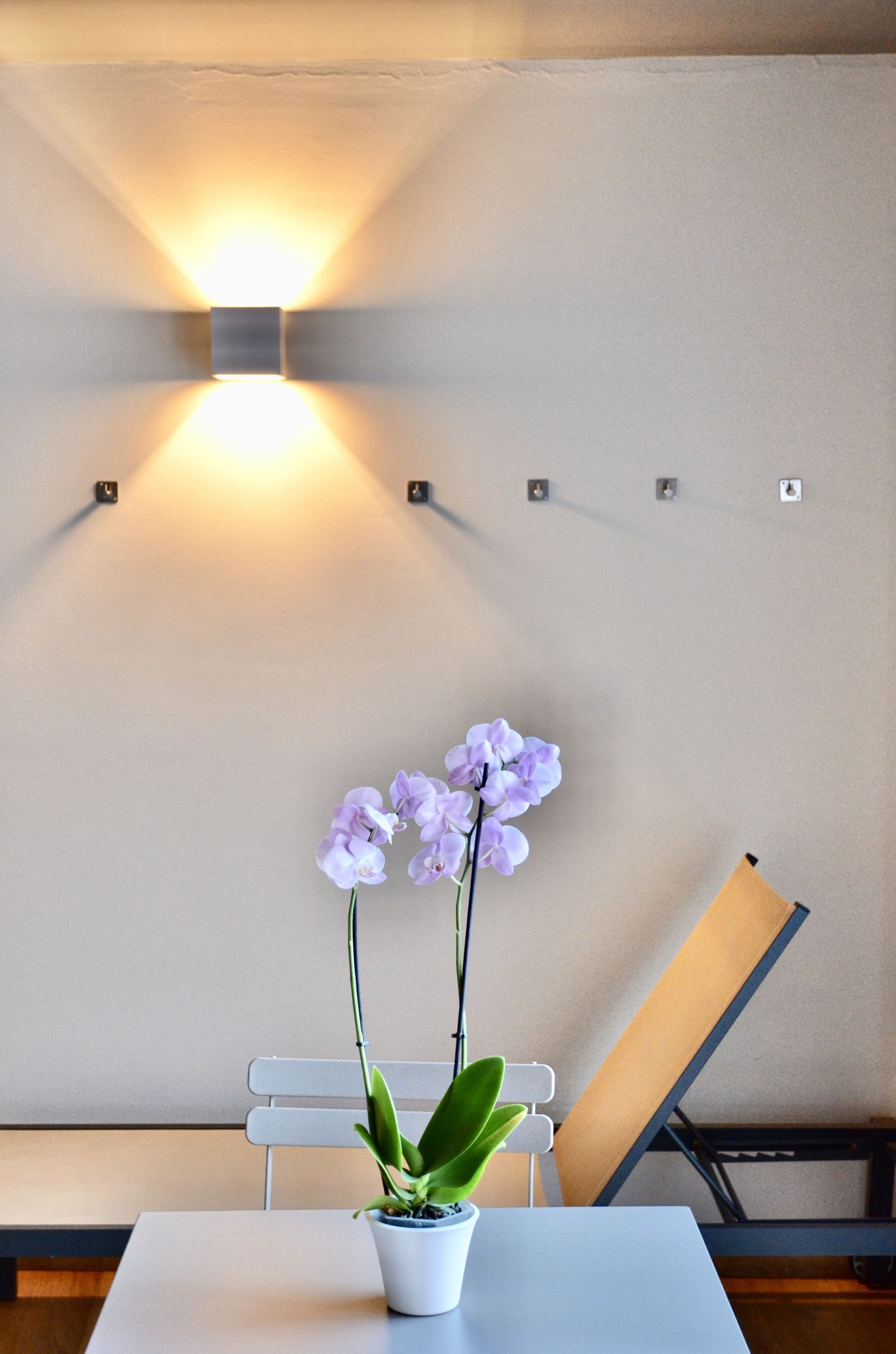 A room with a white table, a potted orchid, and a white chair.