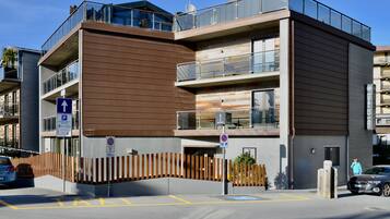 A modern multi-story building with a flat roof, large windows, and balconies.