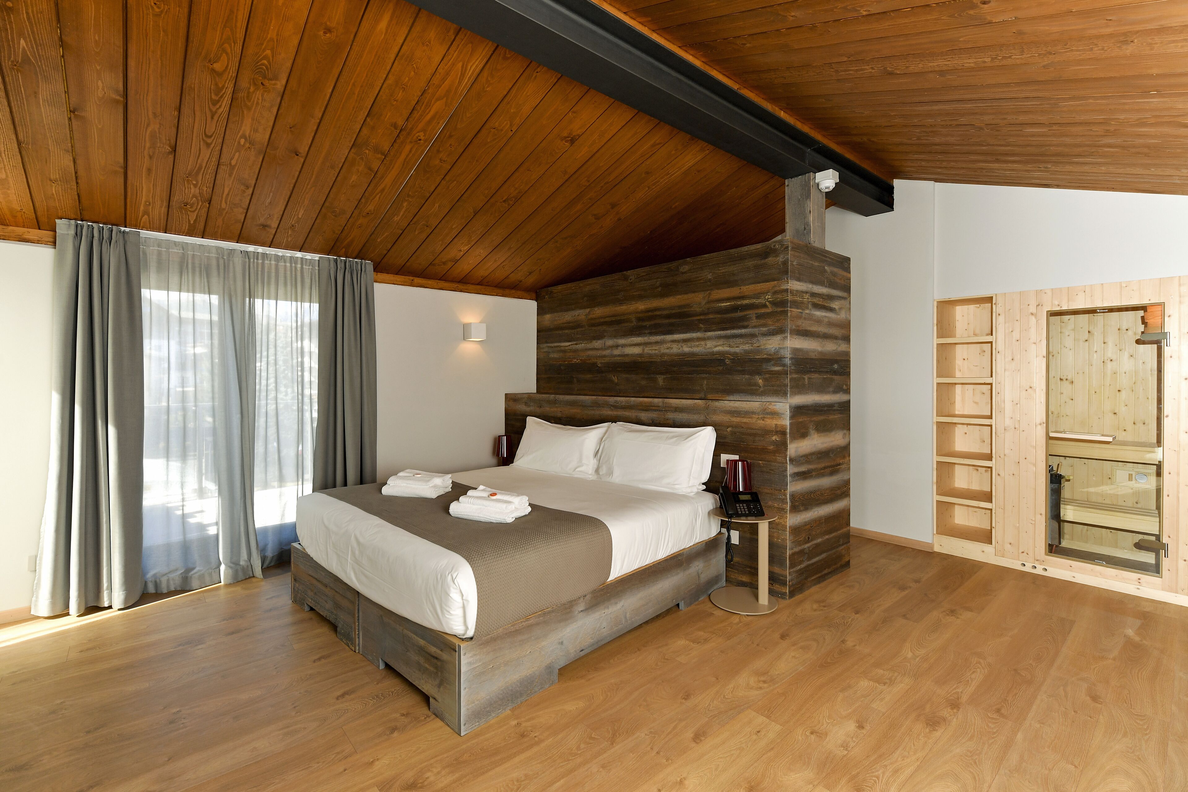 A spacious bedroom with a large bed, wooden ceiling, and a built-in wardrobe.