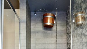 A shower area with a tiled wall, a wooden bucket, and a metal showerhead. - Du Parc Hotel (Sauze d'Oulx)