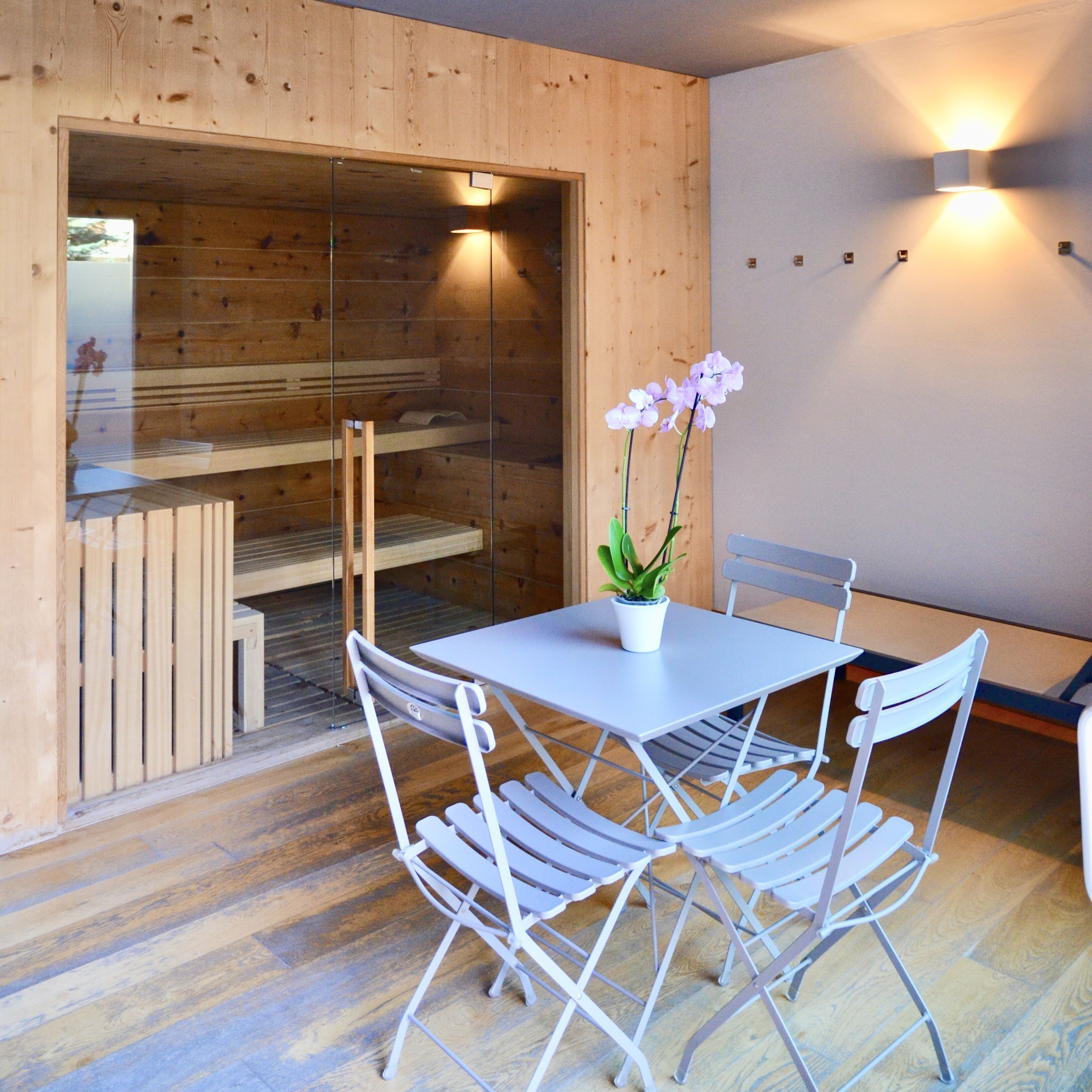 A wooden interior with a table and chairs, a small potted plant, and a bench.