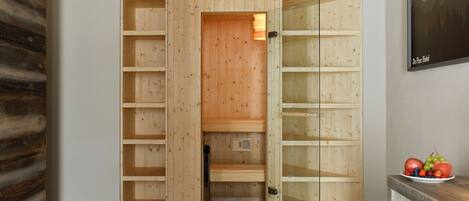 A wooden wardrobe with multiple shelves and a glass door.