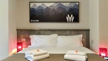 Habitación de hotel con una cama, dos almohadas, un cabecero, un cuadro en la pared y dos lámparas de noche.