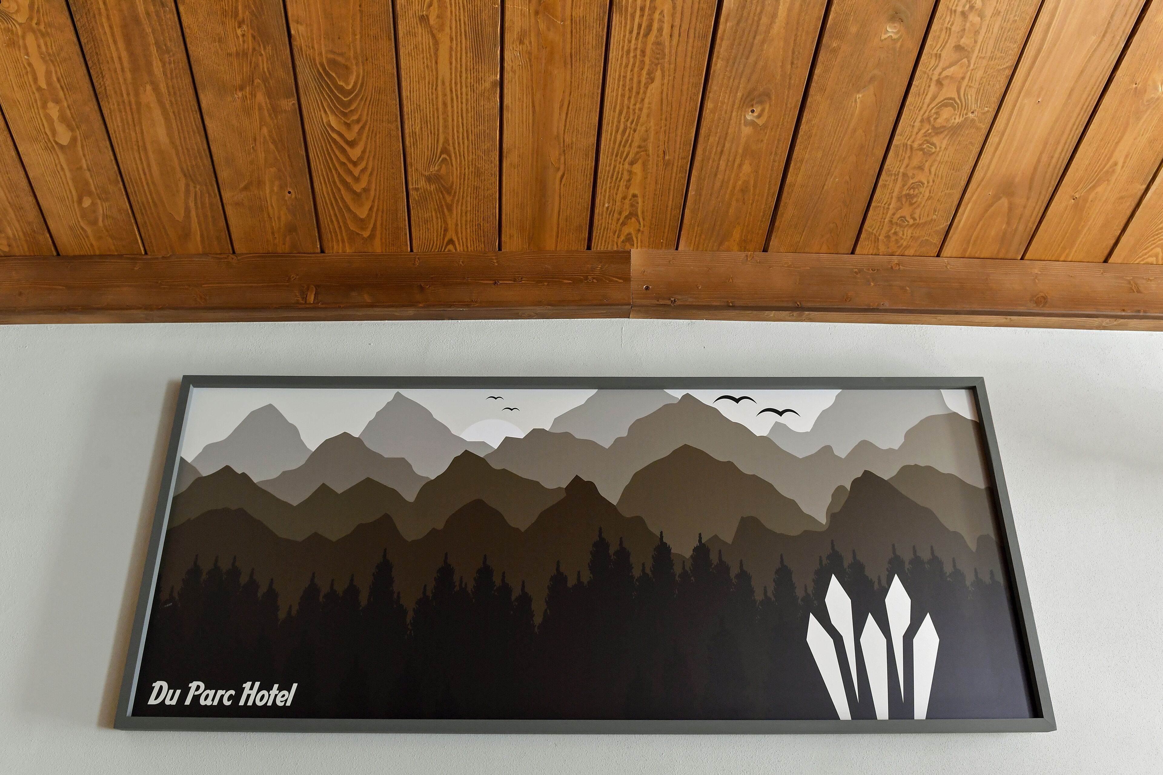 Obra enmarcada que muestra un paisaje montañoso con el texto "Du Parc Hotel" en la parte inferior.