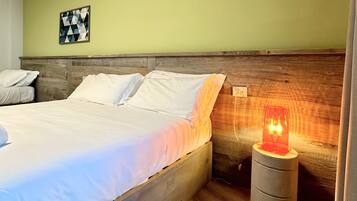A neatly made bed with white linens, a wooden headboard, and a small bedside table with a red lamp.