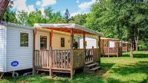 Una hilera de casas móviles con terrazas y porches de madera, rodeadas de árboles.