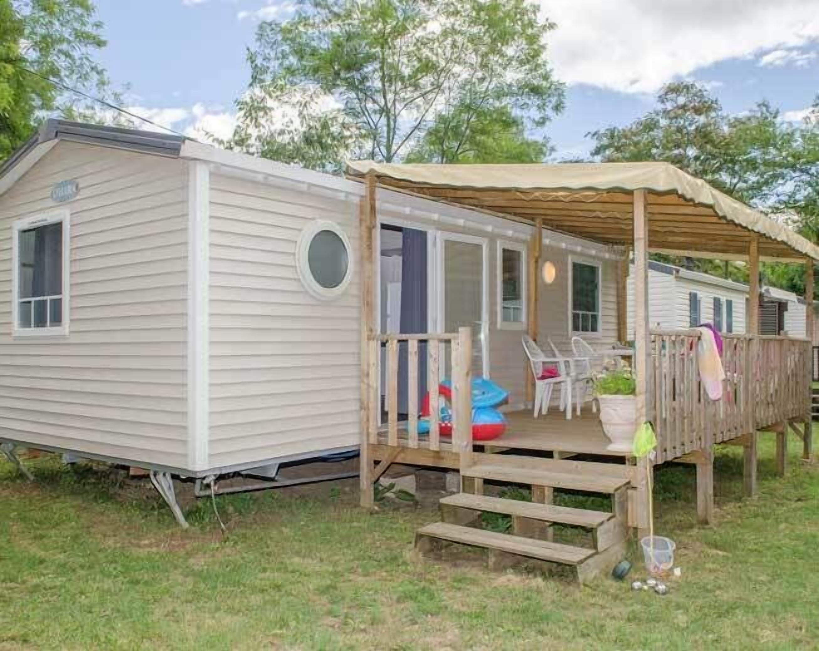 A mobile home with a covered porch and outdoor seating area.