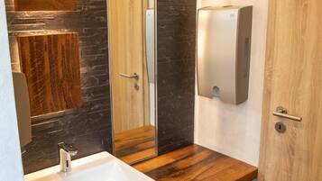 Un bagno moderno con un mobile bagno in legno, un grande specchio, un lavandino bianco e un asciugamani ad aria.