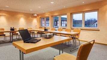 A conference room with multiple tables, chairs, and a laptop on one table.