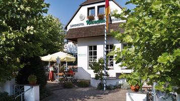 Un Landhotel con terraza exterior, una bandera y un letrero para una taberna.